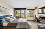 Experience luxury mountain living in this stunning bedroom featuring a plush blue velvet bed and a cozy fireplace.