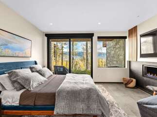 Experience luxury mountain living in this stunning bedroom featuring a plush blue velvet bed and a cozy fireplace.