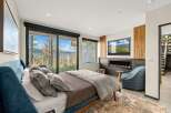 Experience luxury mountain living in this stunning bedroom featuring a modern gas fireplace and a large flat-screen TV.