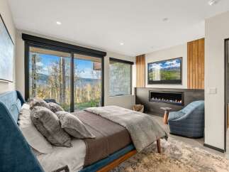 Experience luxury mountain living in this stunning bedroom featuring a modern gas fireplace and a large flat-screen TV.