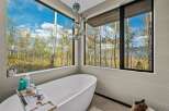 Experience ultimate relaxation in this luxurious bathroom, featuring a stunning freestanding bathtub with panoramic views of a vibrant autumn forest.