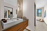Experience modern luxury in this stunning bathroom, featuring a sleek vessel sink atop a rich walnut vanity.