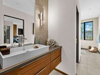 Experience modern luxury in this stunning bathroom, featuring a sleek vessel sink atop a rich walnut vanity.