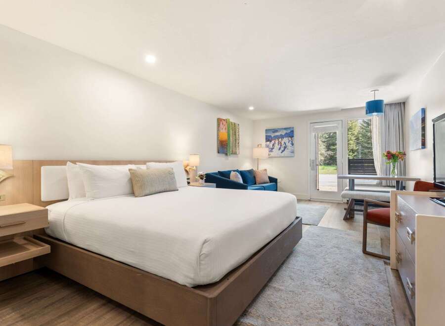 Experience comfort and style in this beautifully appointed hotel room, featuring a spacious king-sized bed with crisp white linens and plush pillows.