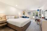 Experience comfort and style in this beautifully appointed hotel room, featuring a spacious king-sized bed with crisp white linens and plush pillows.