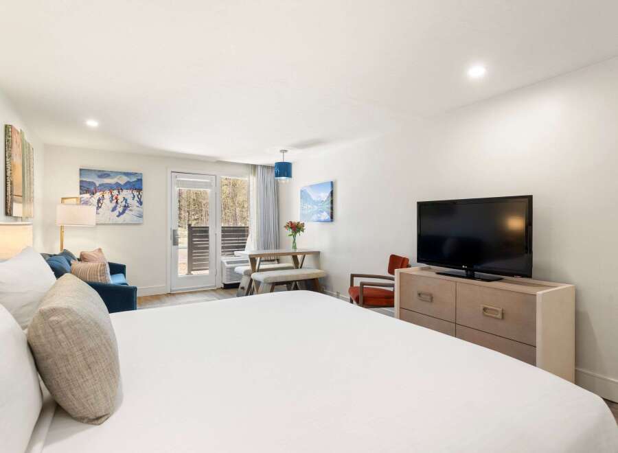 Experience comfort and style in this well-appointed studio suite, featuring a plush king-sized bed and a cozy seating area with a sofa and armchair.