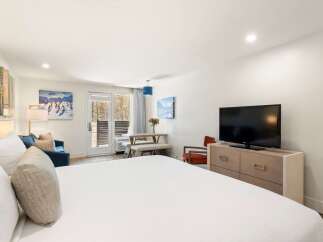 Experience comfort and style in this well-appointed studio suite, featuring a plush king-sized bed and a cozy seating area with a sofa and armchair.