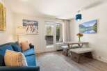 Experience mountain living in this charming studio, featuring a cozy blue sofa and a rustic dining area perfect for intimate meals.