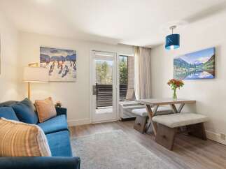 Experience mountain living in this charming studio, featuring a cozy blue sofa and a rustic dining area perfect for intimate meals.