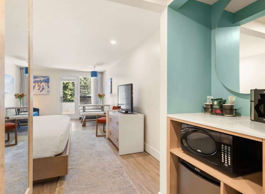 This hotel room offers a comfortable and convenient stay with a plush bed and a dining area perfect for meals or work.