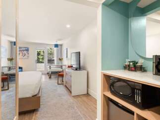 This hotel room offers a comfortable and convenient stay with a plush bed and a dining area perfect for meals or work.