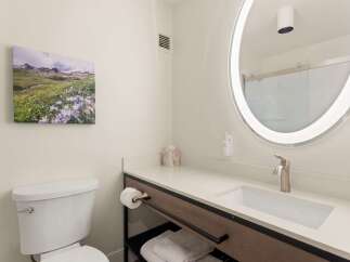 Experience comfort and style in this modern bathroom, featuring a sleek vanity with a built-in sink and a brushed nickel faucet.