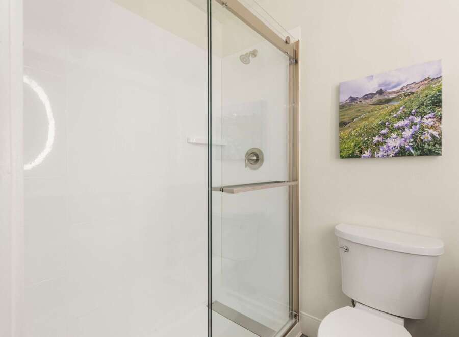 This modern bathroom features a sleek glass-enclosed shower with brushed nickel fixtures, perfect for a refreshing start to your day.