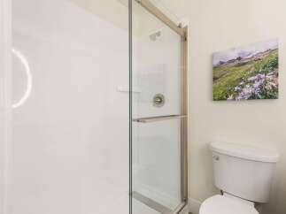 This modern bathroom features a sleek glass-enclosed shower with brushed nickel fixtures, perfect for a refreshing start to your day.