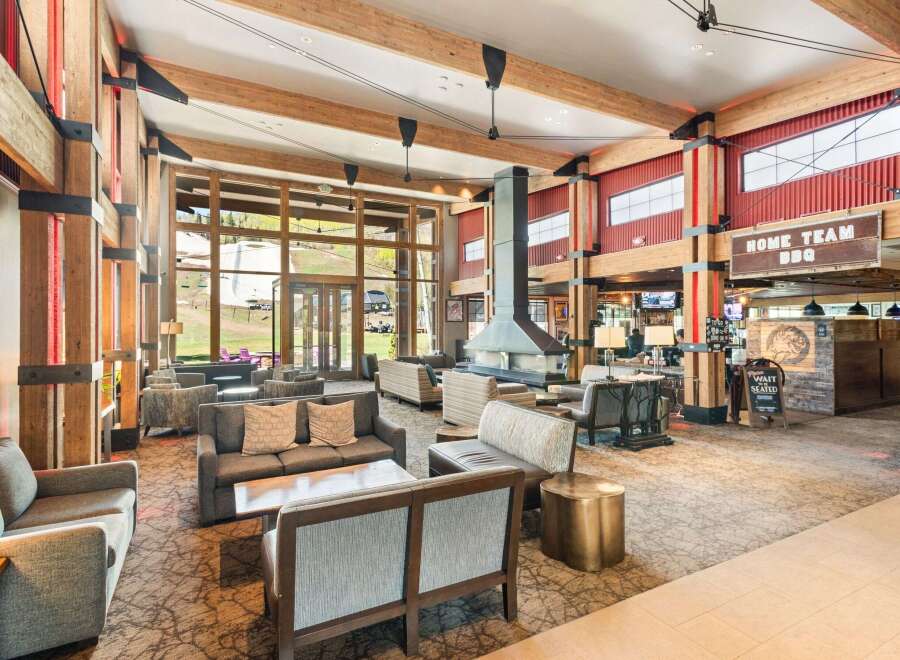 Experience the ultimate mountain lodge ambiance in this spacious lobby, featuring a grand stone fireplace and exposed wooden beams.