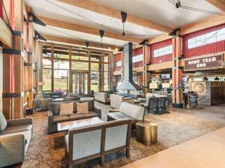 Experience the ultimate mountain lodge ambiance in this spacious lobby, featuring a grand stone fireplace and exposed wooden beams.