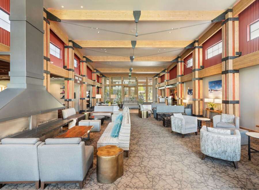 Experience the warmth and grandeur of this spacious lodge lobby, featuring a striking modern fireplace and exposed wooden beams.
