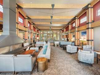 Experience the warmth and grandeur of this spacious lodge lobby, featuring a striking modern fireplace and exposed wooden beams.