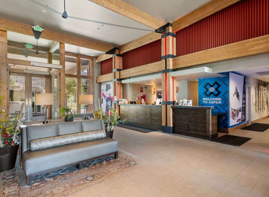 Experience a warm welcome at this hotel lobby, featuring a rustic yet modern design with exposed wooden beams and a cozy seating area.