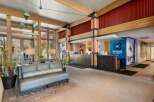 Experience a warm welcome at this hotel lobby, featuring a rustic yet modern design with exposed wooden beams and a cozy seating area.