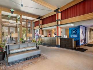 Experience a warm welcome at this hotel lobby, featuring a rustic yet modern design with exposed wooden beams and a cozy seating area.