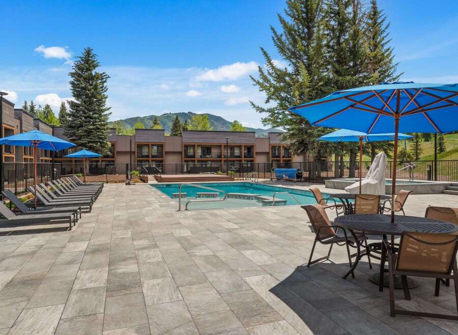 Enjoy a refreshing dip in the sparkling blue pool, surrounded by comfortable lounge chairs and shaded by vibrant blue umbrellas.