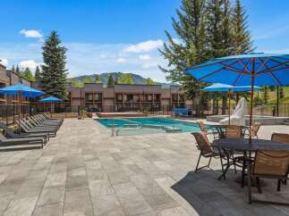 Enjoy a refreshing dip in the sparkling blue pool, surrounded by comfortable lounge chairs and shaded by vibrant blue umbrellas.