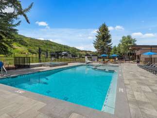 Enjoy a refreshing dip in this stunning outdoor swimming pool, complete with a relaxing hot tub and ample lounge chairs for sunbathing.