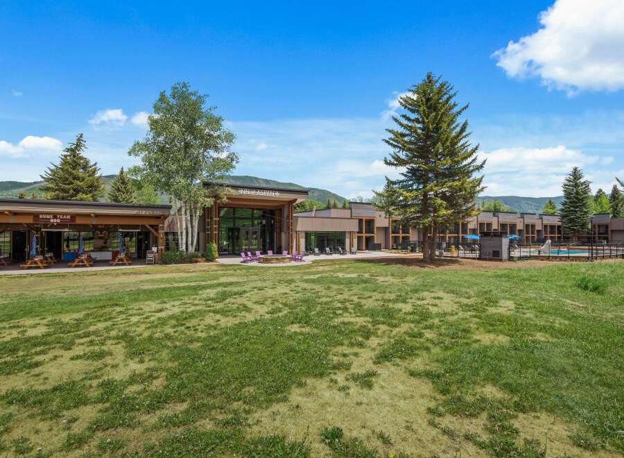 Experience the charm of the Inn at Aspen, a property offering a delightful outdoor seating area with picnic tables and umbrellas, perfect for enjoying a meal al fresco.