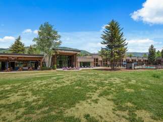Experience the charm of the Inn at Aspen, a property offering a delightful outdoor seating area with picnic tables and umbrellas, perfect for enjoying a meal al fresco.
