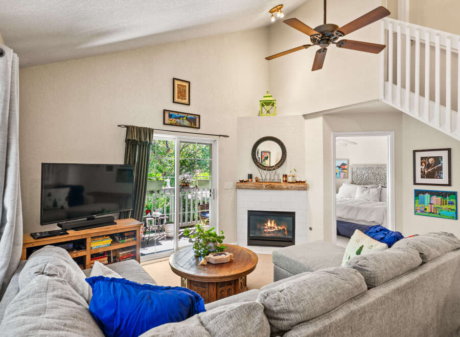 Step into this inviting living room featuring a cozy fireplace and a large sliding glass door that opens to a lush outdoor space.