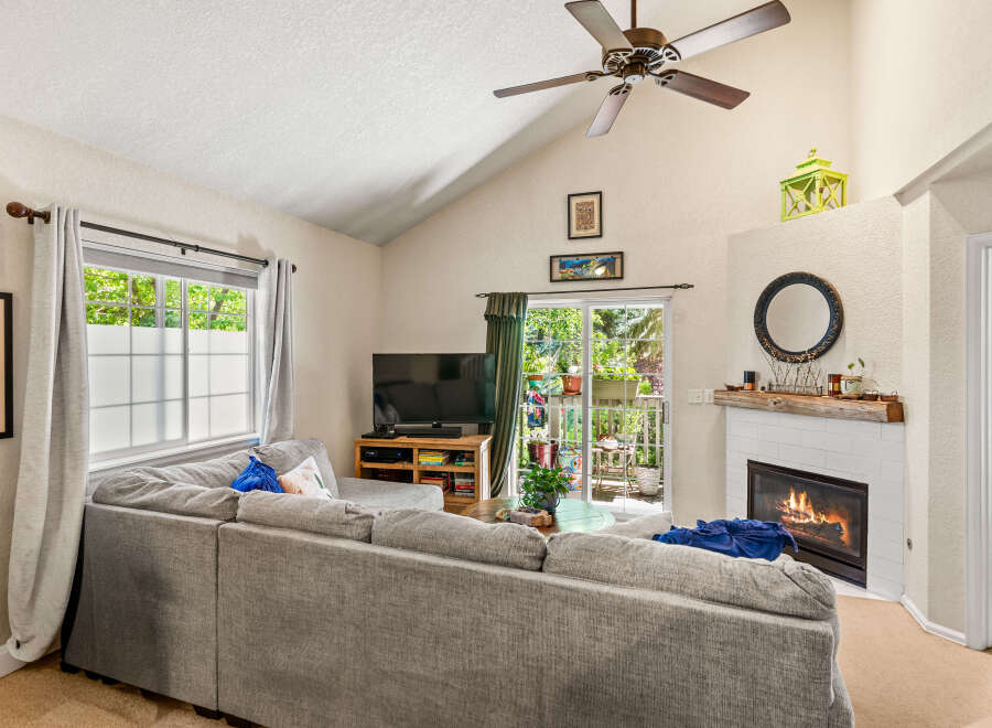 Cozy living room featuring a large sectional sofa facing a TV and a charming fireplace with a rustic wood mantel.