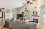 Cozy living room featuring a large sectional sofa facing a TV and a charming fireplace with a rustic wood mantel.