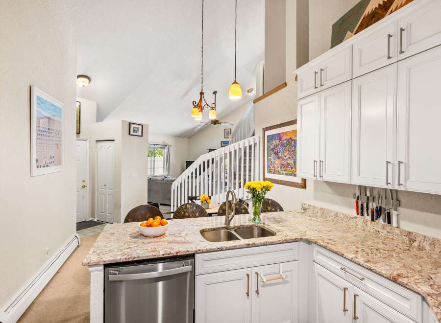 This spacious kitchen boasts beautiful granite countertops and ample white cabinetry, perfect for all your storage needs.