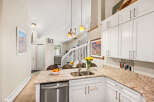 This spacious kitchen boasts beautiful granite countertops and ample white cabinetry, perfect for all your storage needs.