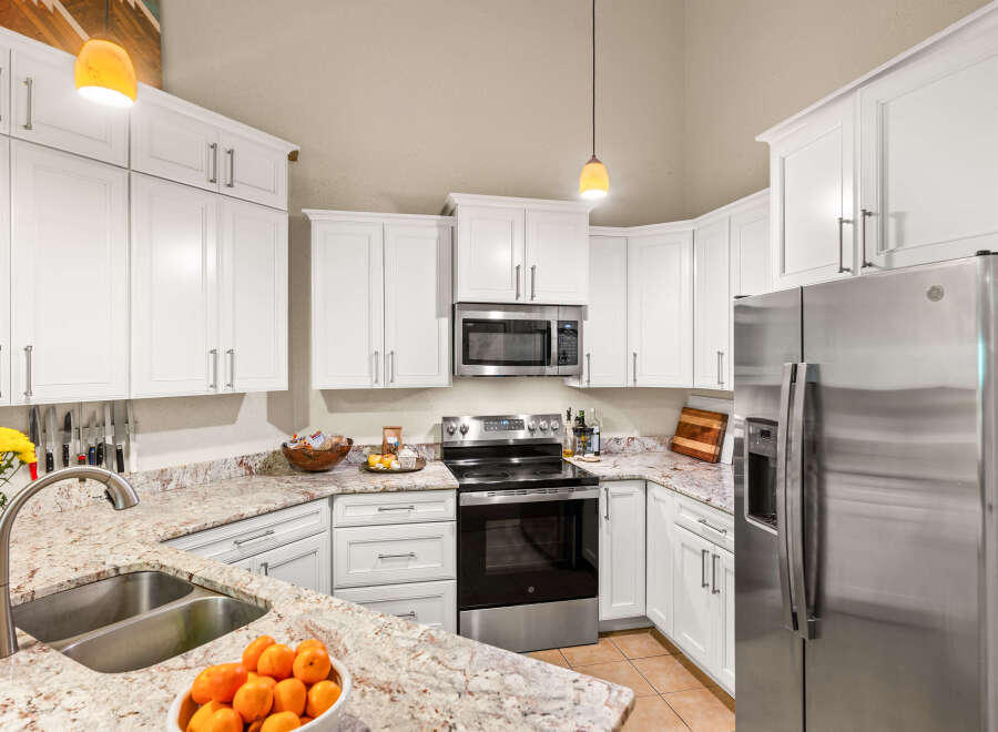 Discover this beautifully updated kitchen, featuring pristine white cabinetry, elegant granite countertops, and a full suite of stainless steel appliances including a refrigerator, microwave, and oven.