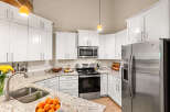 Discover this beautifully updated kitchen, featuring pristine white cabinetry, elegant granite countertops, and a full suite of stainless steel appliances including a refrigerator, microwave, and oven.
