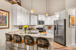 This stunning kitchen boasts pristine white cabinetry, granite countertops, and a large stainless steel refrigerator.