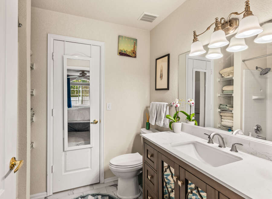 This charming bathroom features a spacious vanity with a marble countertop and a modern sink, complemented by elegant brass fixtures.