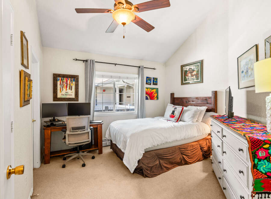 This charming bedroom features a comfortable queen-size bed with crisp white linens and a decorative accent pillow.