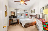 This charming bedroom features a comfortable queen-size bed with crisp white linens and a decorative accent pillow.