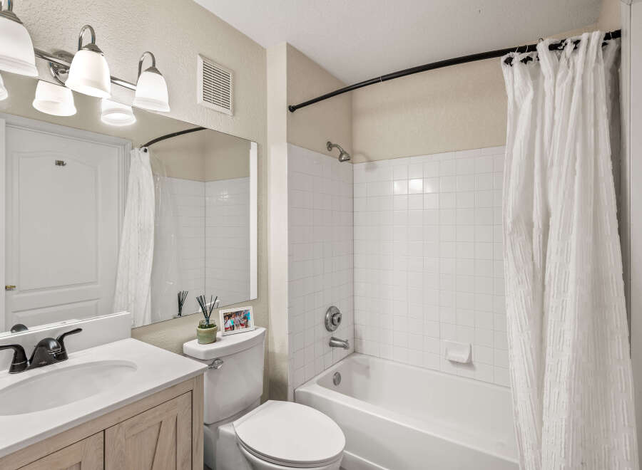 This bathroom features a modern vanity with a sleek black faucet and a white sink, complemented by a large mirror reflecting the space.