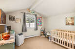 This charming nursery features a cozy crib, a white bookshelf filled with toys and books, and a colorful abstract painting.