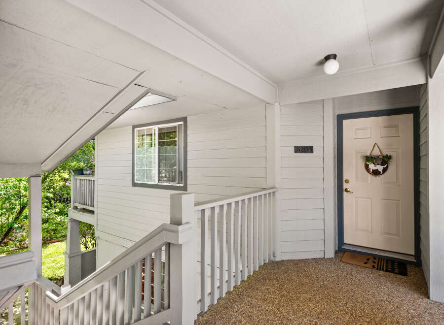 Welcome to this charming property featuring a welcoming front porch with a white railing and a light-colored door.
