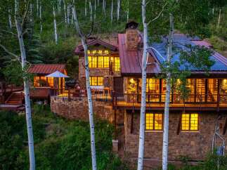 Nestled amidst a serene aspen grove, this stunning stone-clad mountain home offers luxurious living with breathtaking natural surroundings.