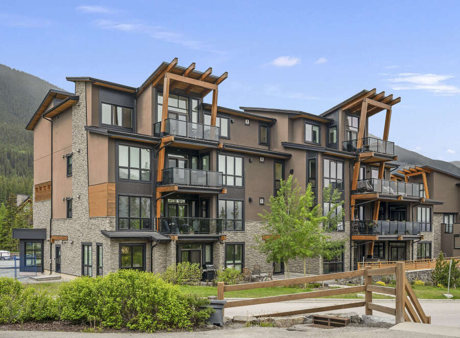 Experience modern mountain living in this stunning condo complex, featuring a striking architectural design with natural wood accents and stone detailing.