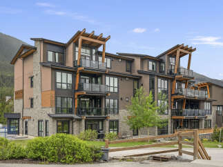 Experience modern mountain living in this stunning condo complex, featuring a striking architectural design with natural wood accents and stone detailing.