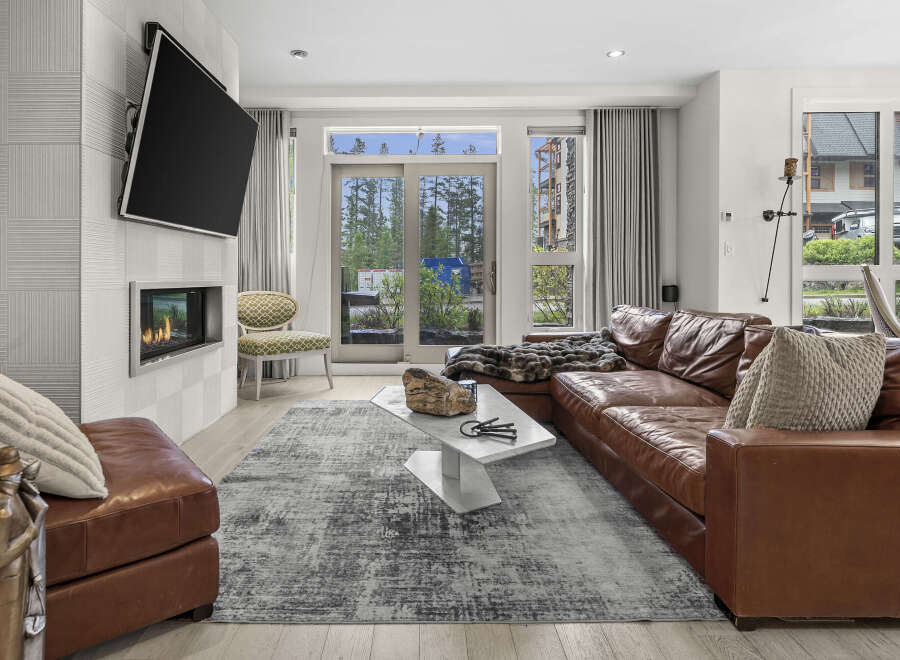 Experience modern living in this stylish living room featuring a sleek fireplace and a large leather sectional.
