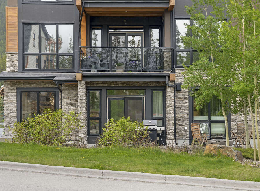 Experience modern mountain living in this stunning property featuring a sleek facade with stone and wood accents.
