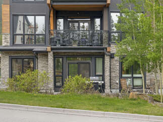 Experience modern mountain living in this stunning property featuring a sleek facade with stone and wood accents.